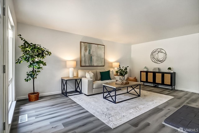 living room featuring wood finished floors, visible vents, and baseboards