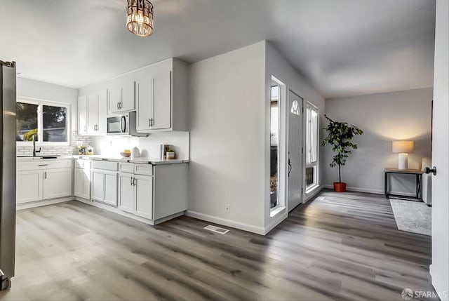 kitchen with tasteful backsplash, visible vents, appliances with stainless steel finishes, light wood-style floors, and a sink