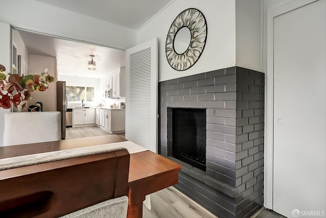 living area with light wood-style floors and a brick fireplace