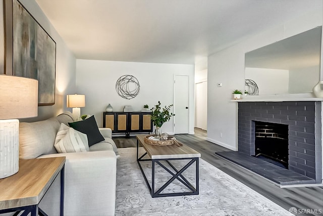 living area with a brick fireplace, baseboards, and wood finished floors