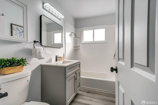 full bath with shower / bathtub combination, wood finished floors, vanity, and toilet