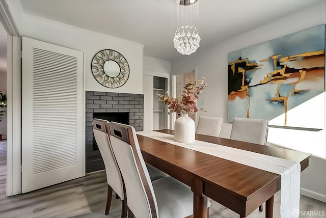 dining room featuring a fireplace, wood finished floors, and a notable chandelier