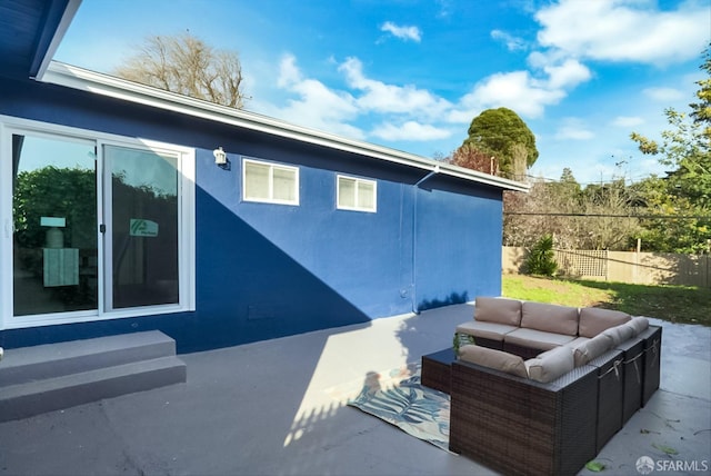 exterior space featuring a patio area, fence, an outdoor hangout area, and stucco siding