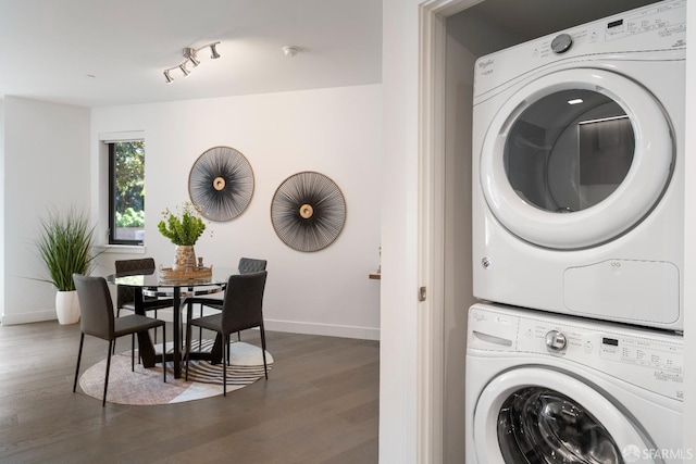 laundry room with baseboards, wood finished floors, laundry area, and stacked washing maching and dryer