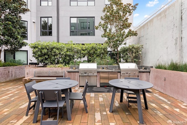 wooden terrace with outdoor dining space, area for grilling, a patio area, and an outdoor kitchen