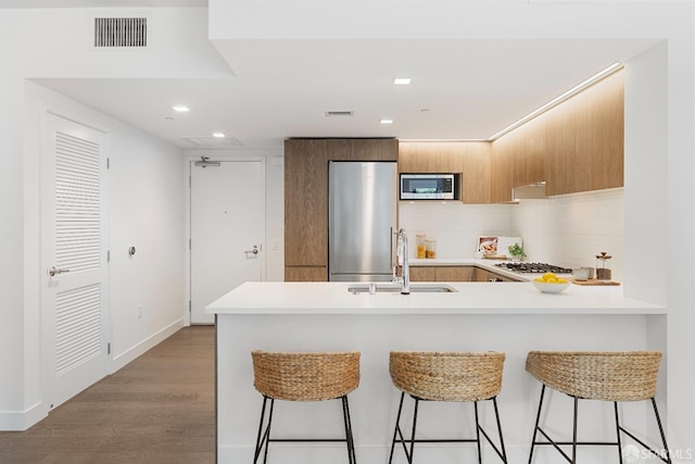 kitchen with visible vents, light countertops, appliances with stainless steel finishes, a peninsula, and a sink