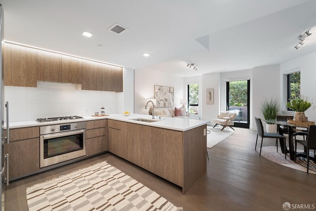 kitchen featuring visible vents, a peninsula, a sink, appliances with stainless steel finishes, and open floor plan