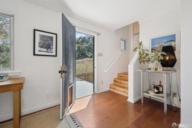 doorway to outside with a healthy amount of sunlight, stairs, and dark wood-style flooring