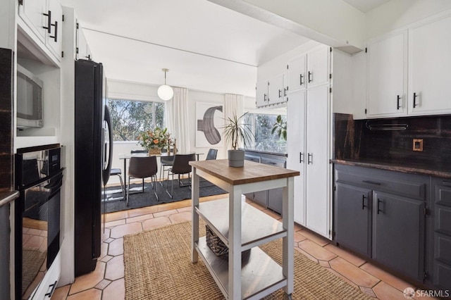 kitchen featuring light tile patterned flooring, decorative backsplash, white cabinetry, and black appliances