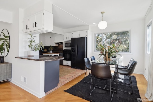 kitchen with visible vents, backsplash, a peninsula, white cabinets, and black appliances