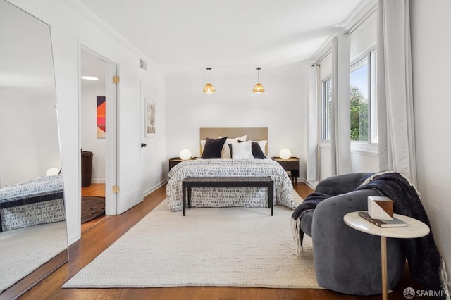 bedroom with visible vents, wood finished floors, and crown molding