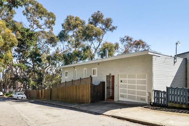 view of front facade with fence, a garage, and stucco siding