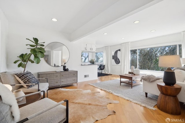 living room featuring visible vents, baseboards, light wood-style flooring, recessed lighting, and beamed ceiling