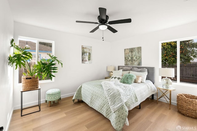 bedroom with light wood-style floors, baseboards, and a ceiling fan