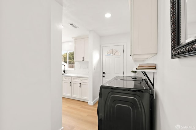 laundry room with washer / dryer, visible vents, light wood-type flooring, a sink, and recessed lighting