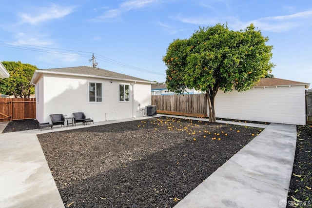 view of side of property featuring a patio, central AC, a fenced backyard, and stucco siding