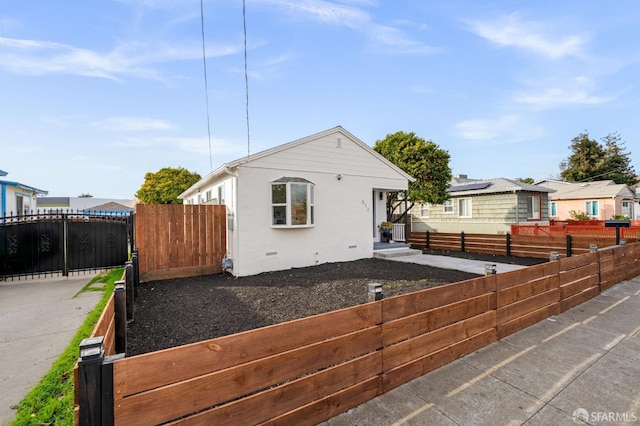 view of front of house featuring crawl space, a fenced front yard, a residential view, and stucco siding