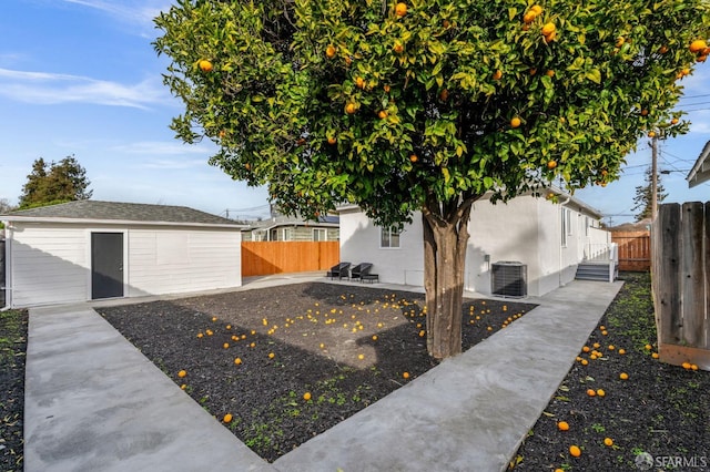 view of yard featuring an outbuilding, a patio area, cooling unit, and fence