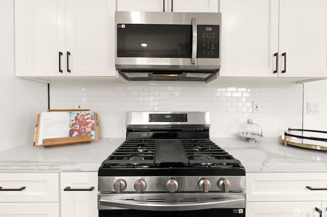 kitchen featuring appliances with stainless steel finishes, backsplash, light stone countertops, and white cabinets