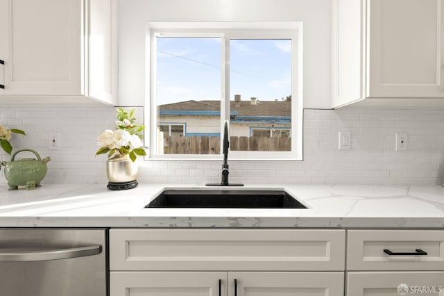 kitchen featuring light stone countertops, a sink, white cabinetry, decorative backsplash, and dishwasher