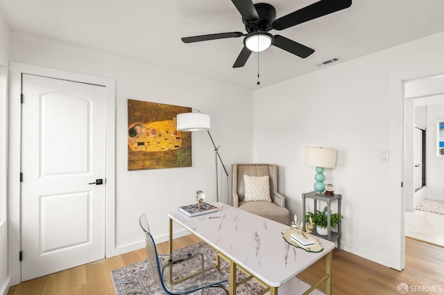 office area with ceiling fan, light wood finished floors, visible vents, and baseboards