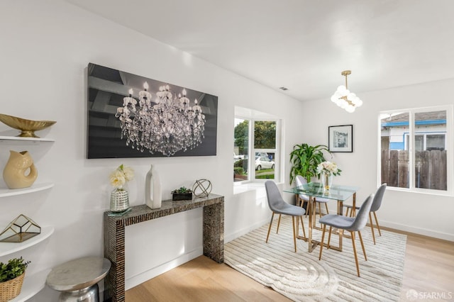 dining room featuring lofted ceiling, light wood-type flooring, and baseboards