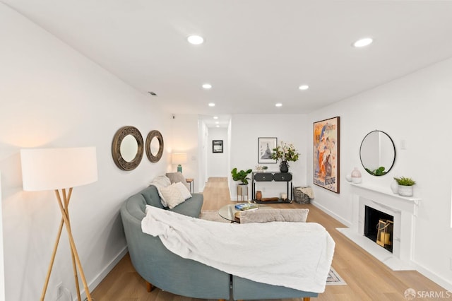 living area featuring light wood-type flooring, a fireplace, baseboards, and recessed lighting