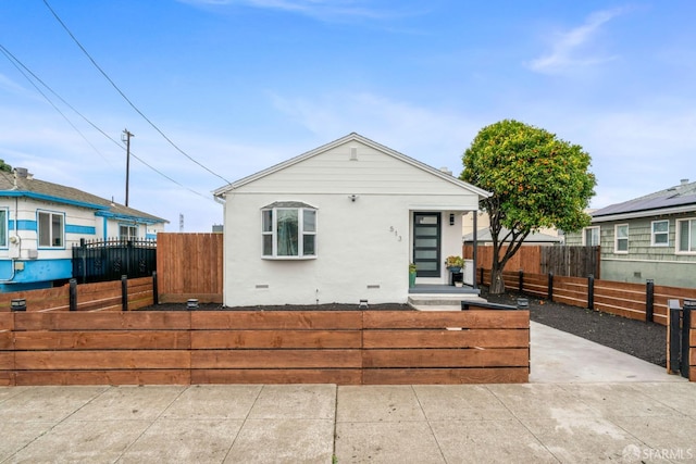 bungalow featuring crawl space, a fenced front yard, and stucco siding