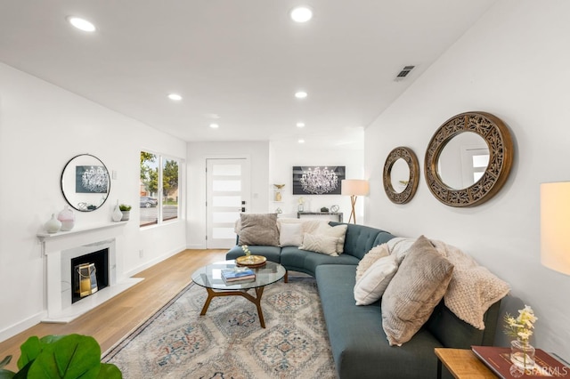 living room with visible vents, baseboards, a premium fireplace, light wood-type flooring, and recessed lighting