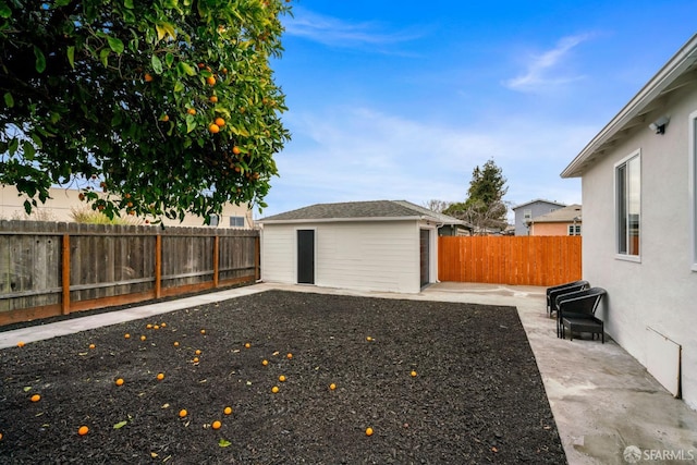 view of yard featuring a fenced backyard, an outdoor structure, and a patio