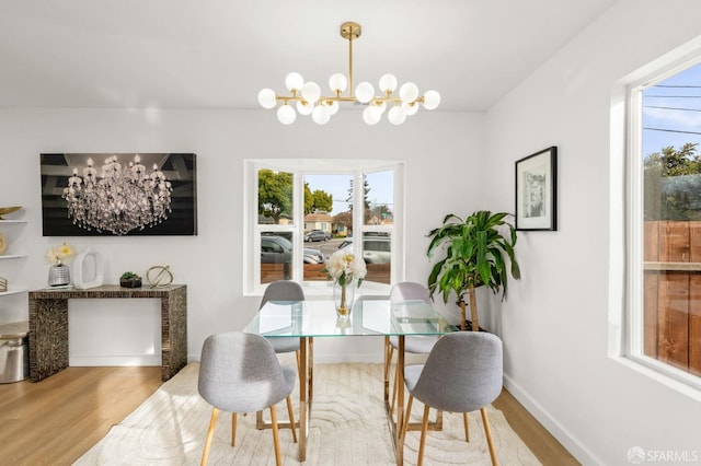 dining area featuring a chandelier, baseboards, and wood finished floors