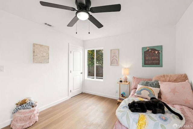 bedroom featuring ceiling fan, light wood-style flooring, visible vents, and baseboards