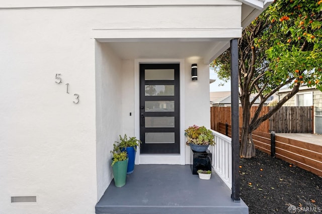 doorway to property featuring fence and stucco siding