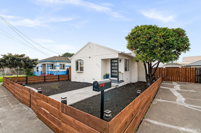 bungalow with a fenced front yard and stucco siding