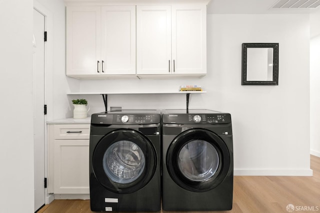 clothes washing area with visible vents, baseboards, washer and dryer, cabinet space, and light wood finished floors