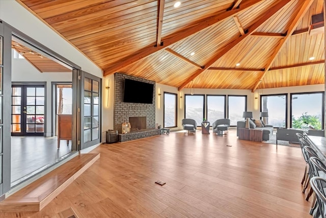 interior space with wood ceiling, light wood-type flooring, high vaulted ceiling, and a brick fireplace