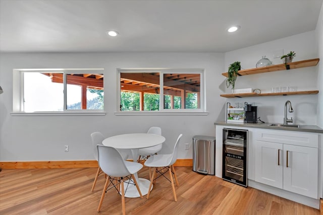 interior space with white cabinets, light hardwood / wood-style floors, wine cooler, and sink