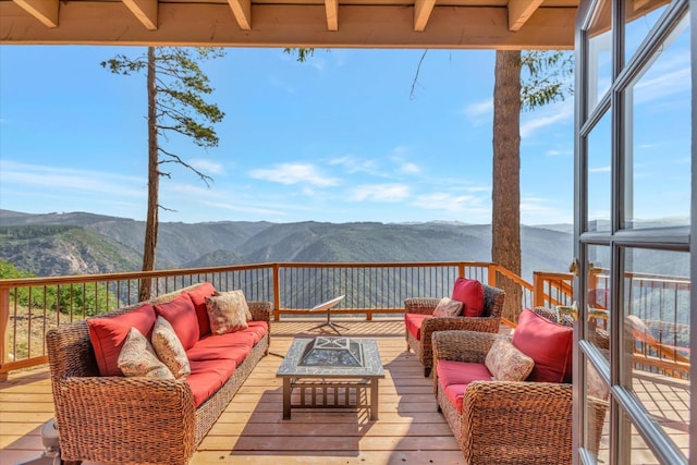 wooden deck with a mountain view and an outdoor living space with a fire pit