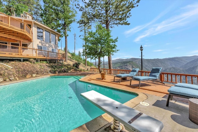 view of pool with a deck with mountain view, a patio, and a diving board