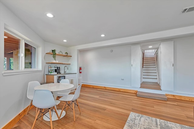 dining room featuring light hardwood / wood-style floors, wine cooler, and sink