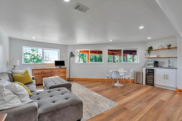 living room with indoor wet bar, light wood-type flooring, and wine cooler