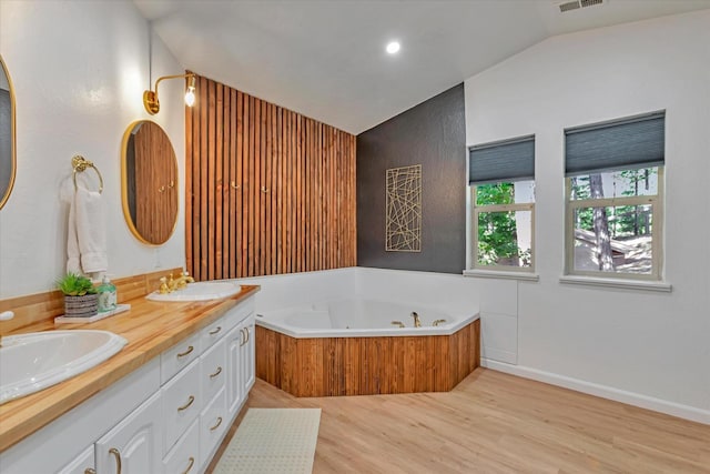 bathroom with a tub to relax in, hardwood / wood-style floors, vanity, and lofted ceiling