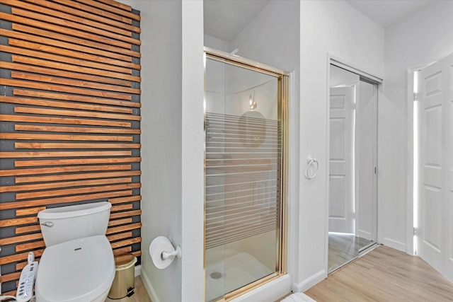 bathroom with hardwood / wood-style floors, toilet, and a shower with shower door