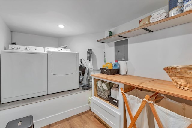 laundry area with washer and clothes dryer, electric panel, and light hardwood / wood-style flooring