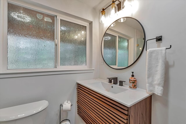 bathroom with vanity, toilet, and a healthy amount of sunlight