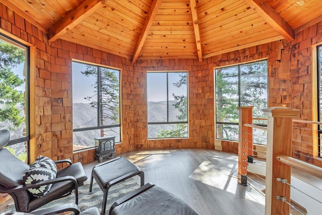 sunroom / solarium with a wood stove, a mountain view, wooden ceiling, and vaulted ceiling with beams