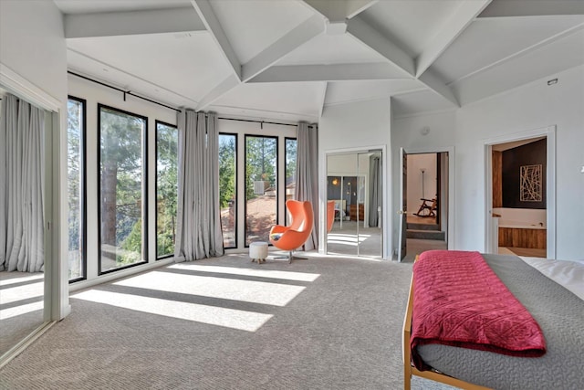 carpeted bedroom with beam ceiling, multiple windows, and ensuite bathroom