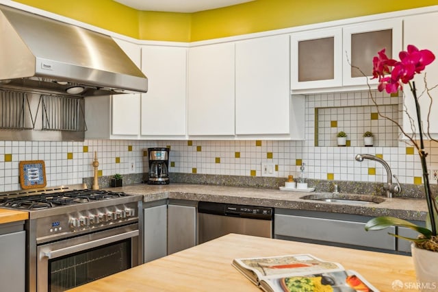 kitchen featuring wood counters, range hood, sink, white cabinets, and stainless steel appliances