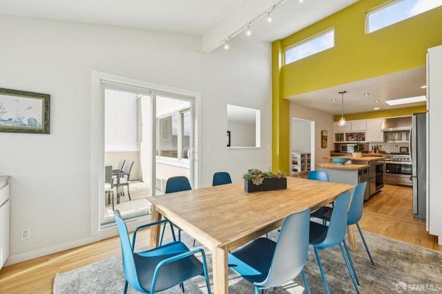 dining space with track lighting and light hardwood / wood-style flooring