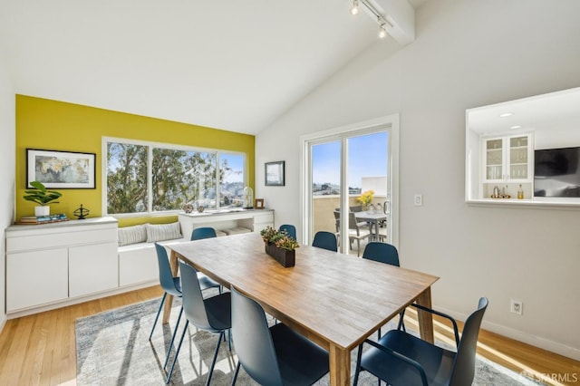 dining space with vaulted ceiling, light hardwood / wood-style floors, and track lighting